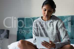 Relaxed woman using digital tablet on bed