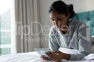 Young woman using digital tablet on bed