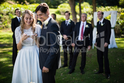 Bride and groom reviewing photographs on mobile phone