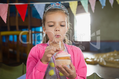 Birthday girl blowing candle on a cupcake