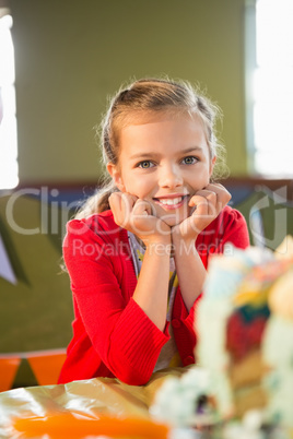 Portrait of cute girl sitting at table during birthday party