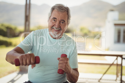 Smiling senior man exercising with dumbbells