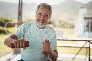 Smiling senior man exercising with dumbbells