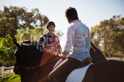 Two male friends riding horse in the ranch