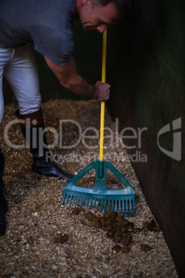 Man using broom to clean the stable