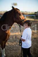 Rider boy caressing a horse in the ranch
