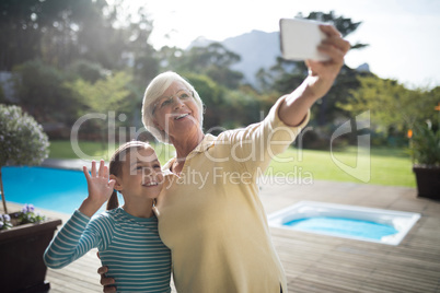 Granddaughter and grandmother taking a selfie near the pool