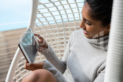 Woman holding digital tablet on swing chair