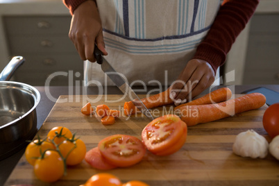 Mid section of woman cutting carrot at counter