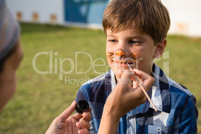 Cropped hand doing face paint on boy