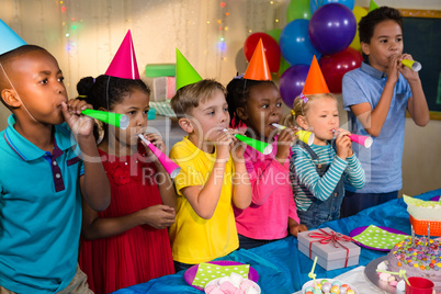 Playful children blowing party horns