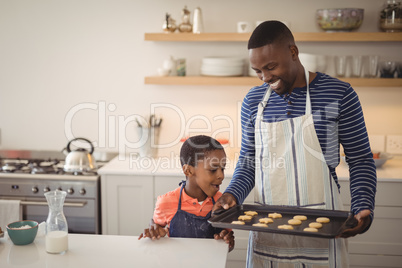 Father holding tray while son looking at cookies