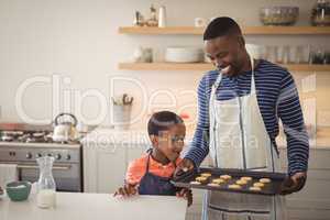 Father holding tray while son looking at cookies