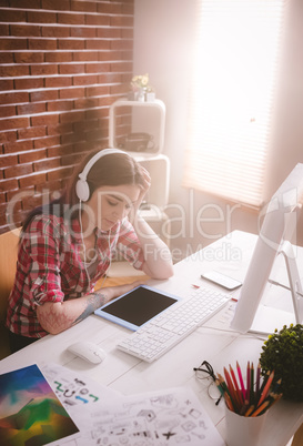 Smiling executive listening music on digital tablet