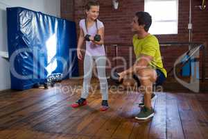 Trainer assisting teenage girl in exercise