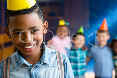Portrait of boy wearing suspenders with friends in background