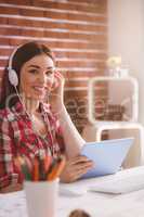 Smiling executive listening music on digital tablet in office