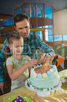 Father and daughter decorating birthday cake