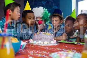 children with clown blowing candles on cake