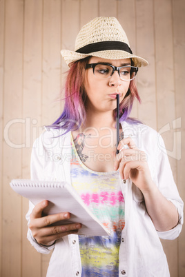 Thoughtful woman holding notepad and pen