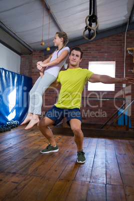 Trainer lifting teenage girl while exercising