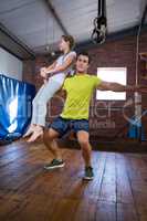 Trainer lifting teenage girl while exercising