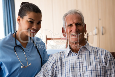 Portrait of female doctor with senior man sitting in nursing home