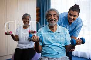 Nurse training seniors in lifting dumbbells at nursing home