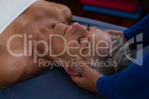 Physiotherapist giving head massage to a senior woman
