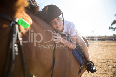 Portrait of cute girl embracing horse in the ranch