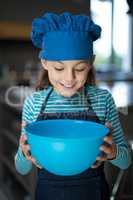 Smiling girl looking into the bowl in the kitchen