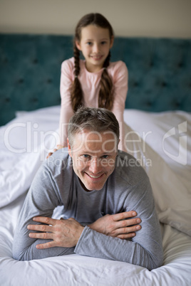 Smiling daughter sitting on fathers back in bedroom Smiling daughter sitting on fathers back in bedroom