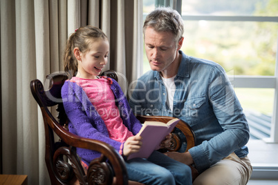 Father and daughter reading a book at home