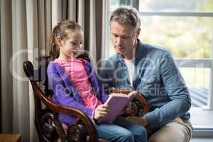 Father and daughter reading a book at home