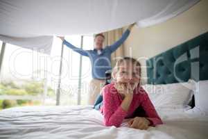 Father spreading a white blanket over his daughter