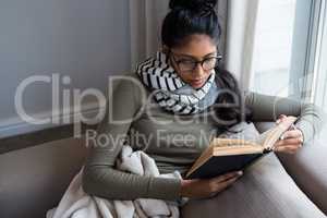 Woman reading book on sofa