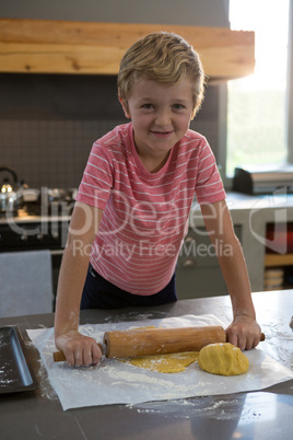 Portrait of smiling boy rolling dough