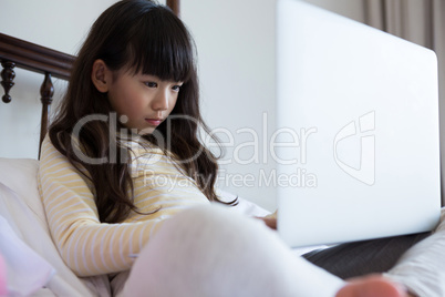 Girl with long hair using laptop on bed