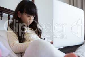 Girl with long hair using laptop on bed