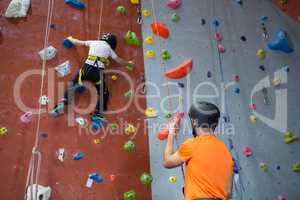 Trainer assisting boy in rock climbing