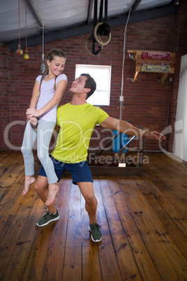 Trainer lifting teenage girl while exercising