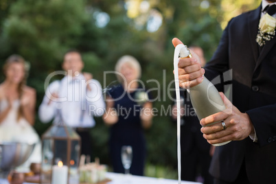 Groom opening champagne bottle at park