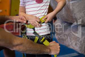 Trainer assisting boy to wear safety harness