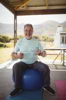 Smiling senior man sitting on fitness ball