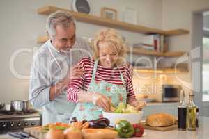 Senior couple mixing vegetables salad in bowl