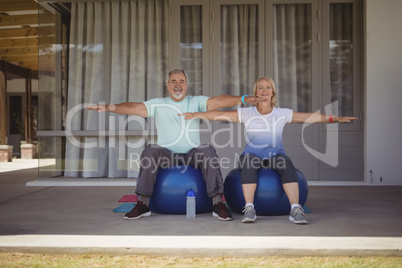 Senior couple doing stretching exercise on exercise ball