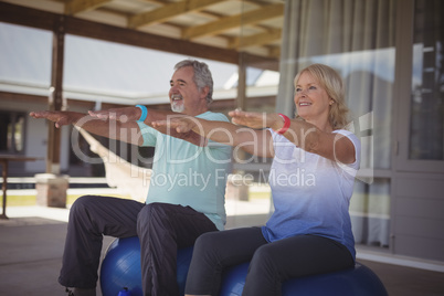 Senior couple exercising on exercise ball