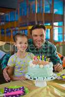 Father and daughter with birthday cake at home