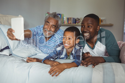 Multi-generation family taking selfie with digital tablet on bed