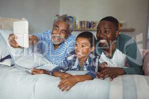 Multi-generation family taking selfie with digital tablet on bed